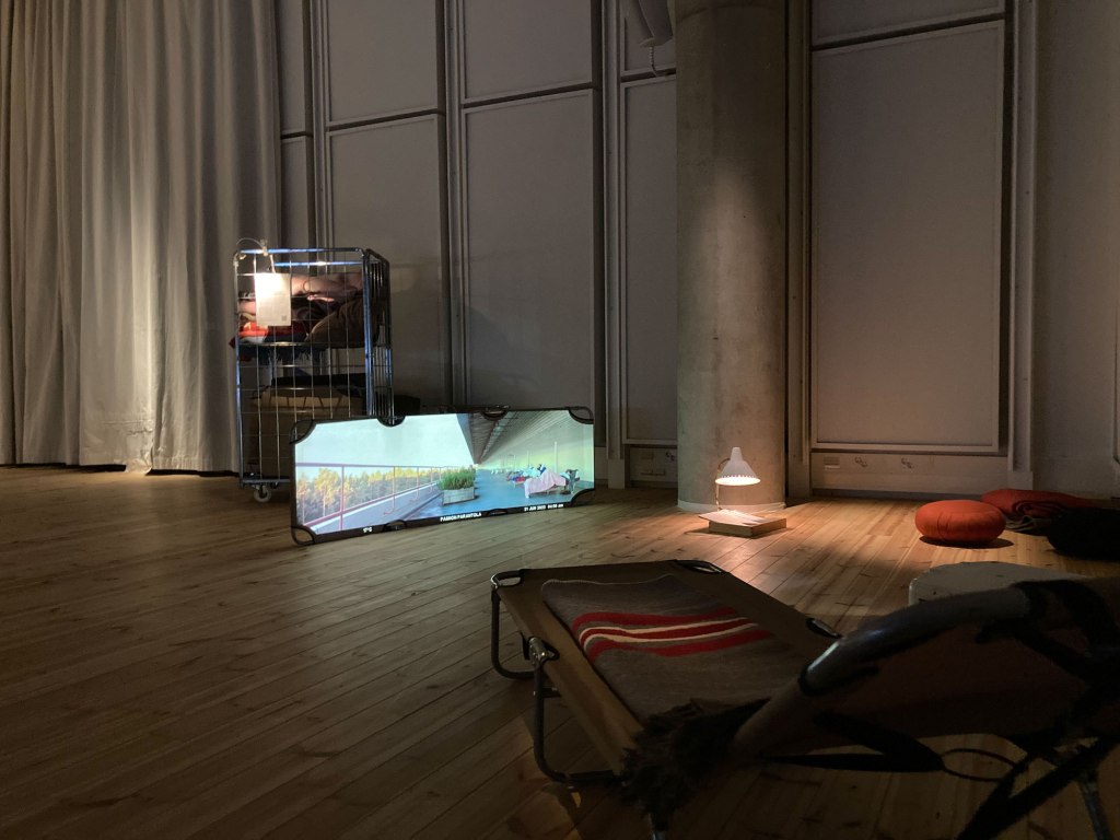 Installation view, Midsummer night goes Sörnäinen (2022), performative event, folding beach chairs, wool blankets, trolley, light, texts, video projection on beach chair, 4 min